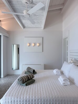 Ein Hotelzimmer mit einem großen Bett, einem Deckenventilator, einem Spiegel und einer Wandleuchte.