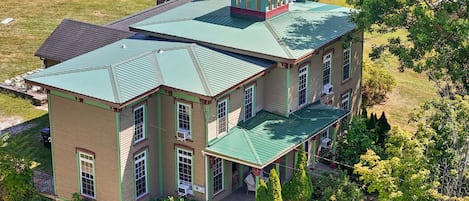 Une grande maison à plusieurs étages, dotée d’un toit végétalisé, de nombreuses fenêtres et d’un porche abrité.