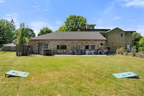 Edificio de piedra con un patio, mobiliario exterior y una parrilla.