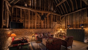 A rustic room with exposed wooden beams, a vintage Supercar model, a Game Zone sign, and a stone wall. - Hilltop Shepherds Hut with Hot Tub and Tennis (Hambleden)