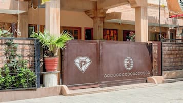 A gated entrance with a potted plant, a diamond-shaped emblem, and a globe symbol on the gate.