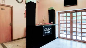 A reception desk with a sign indicating it is company-serviced, a clock on the wall, and a door with a windowed view.