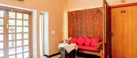 A room with a wooden door labeled 'LORD-1', a red sofa, a small table with a vase, and a large window with a view.
