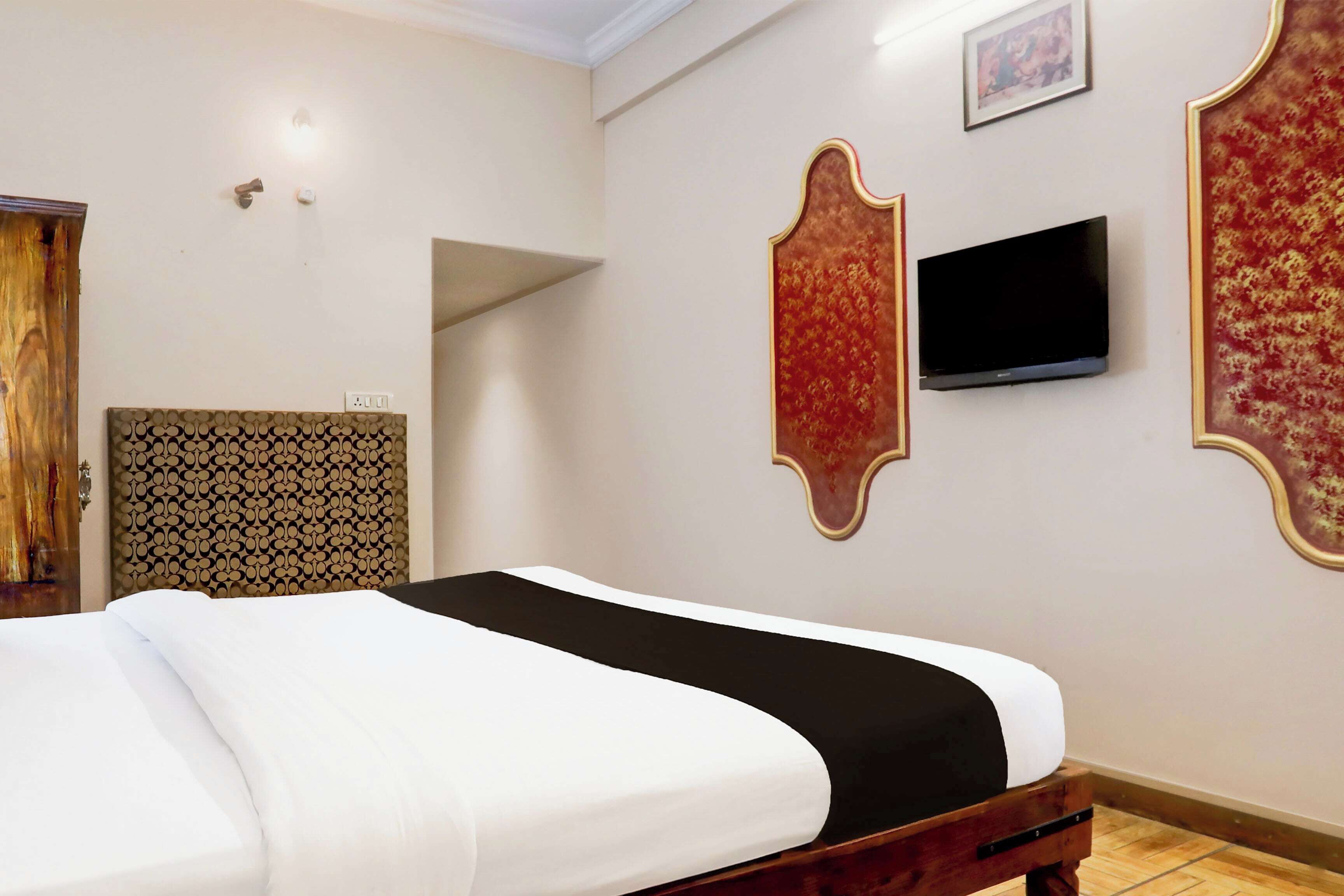 A hotel room with a bed, a television mounted on the wall, and a patterned headboard.