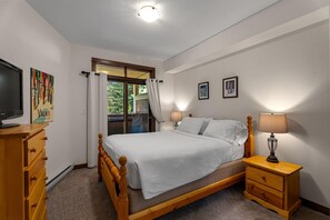Een slaapkamer met een bed, nachtlampjes, een televisie en een dressoir.