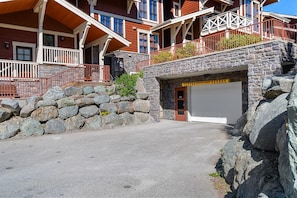 Ein mehrstöckiges Gebäude mit einer Stein-Fassade, einem Garageneingang und einer Steinmauer.