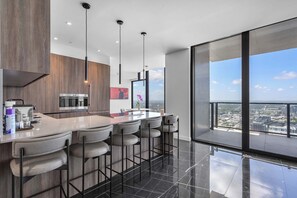 A modern kitchen with a bar area, large windows, and a city view. - Executive Miami Penthouse - 2bdr (Miami)