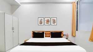 A bedroom with a bed, a wardrobe, and three framed pictures on the wall. - Collection O Iskcon Temple Mansarovar  (Jaipur)