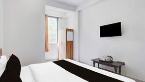 A hotel room with a bed, a bedside table with a kettle, a flat-screen TV, and a window with curtains. - Collection O Iskcon Temple Mansarovar  (Jaipur)