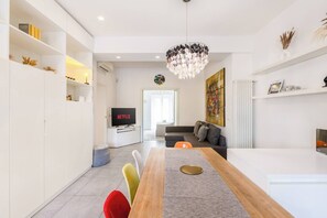 A modern living room with a dining area, a TV displaying 'NETFLIX', and a chandelier. - Garibaldi's Residence (Milan)