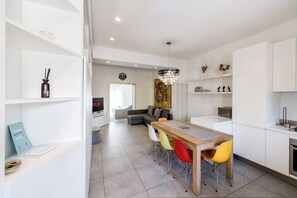 A modern living space with a dining area, a sofa, a TV, and a kitchen. - Garibaldi's Residence (Milan)