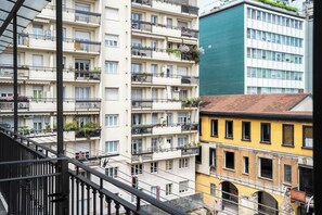 Ein mehrstöckiges Wohngebäude mit Balkonen und einer Treppe, im Hintergrund ein kontrastierendes, modernes Gebäude.