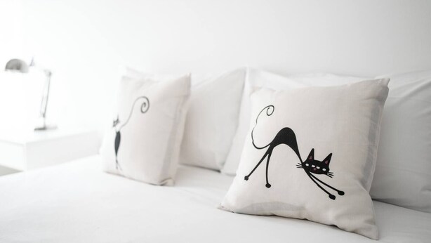A bed with white bedding and two pillows, one with a cat design. - Garibaldi's Residence (Milan)