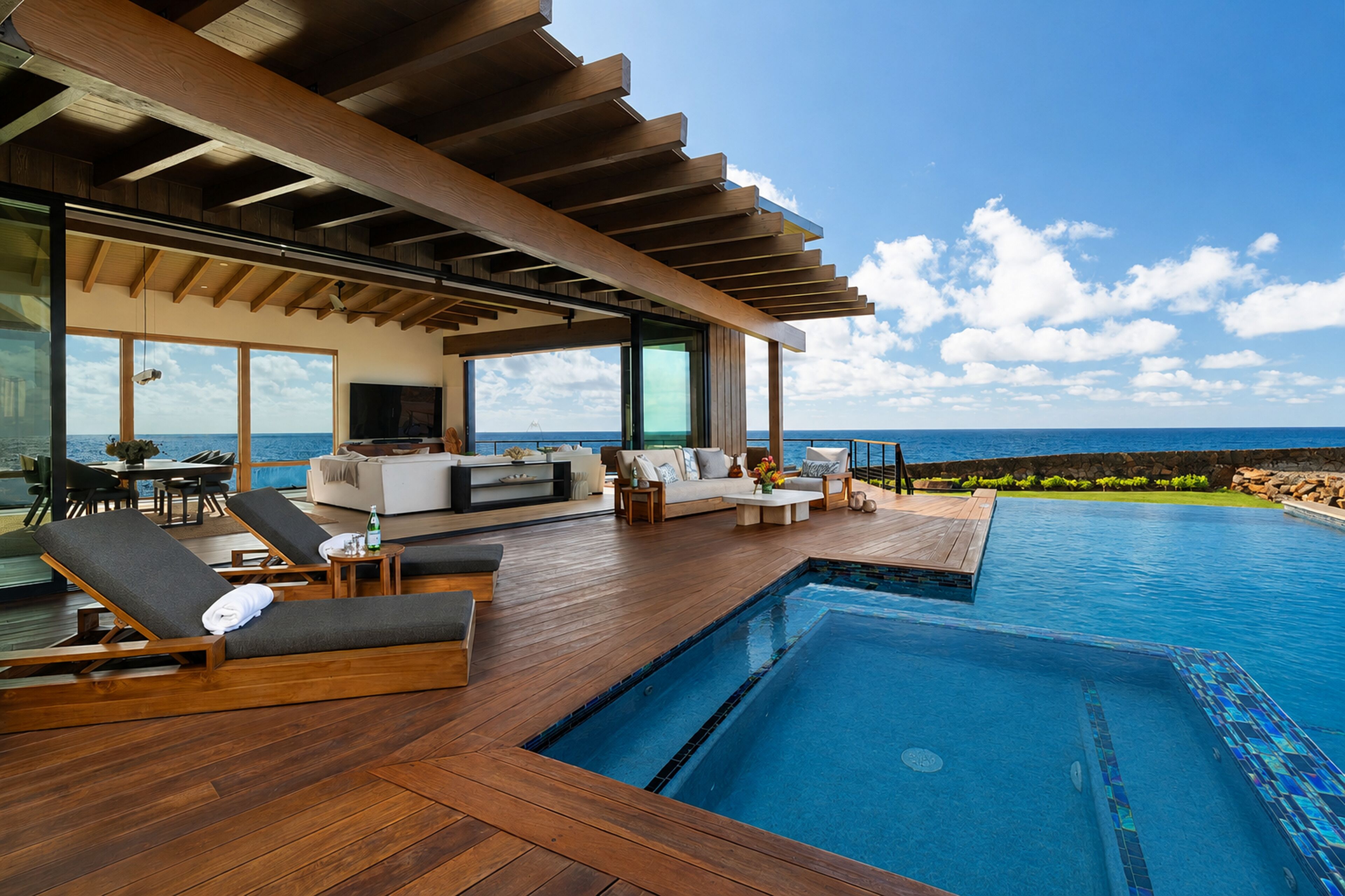 Ein moderner Poolbereich im Freien mit Holzboden, Liegestühlen und Blick auf das Meer.