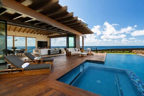 A modern outdoor pool area with wooden decking, lounge chairs, and a view of the ocean. - Hale Kiholo by Alekona Kauai- 5BR Oceanfront Luxury Estate (Koloa)