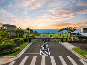 A gated driveway leading to a property with a view of the ocean and a clear sky. - Hale Kiholo by Alekona Kauai- 5BR Oceanfront Luxury Estate (Koloa)
