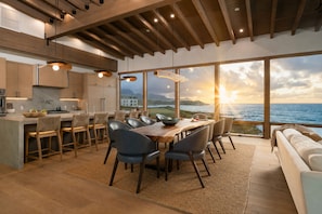 A modern kitchen with wooden cabinets and a dining area with a view of the sea. - Hale Kiholo by Alekona Kauai- 5BR Oceanfront Luxury Estate (Koloa)