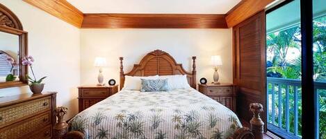 A bedroom with a wooden bed, two bedside tables with lamps, a ceiling fan, and a large window with a view of greenery.