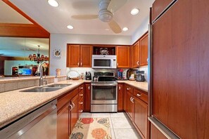 Une cuisine avec des meubles en bois, un four en acier inoxydable, un four à micro-ondes et un lave-vaisselle.