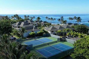 Un quartier résidentiel comprenant plusieurs maisons, un court de tennis et offrant une vue sur l’océan.