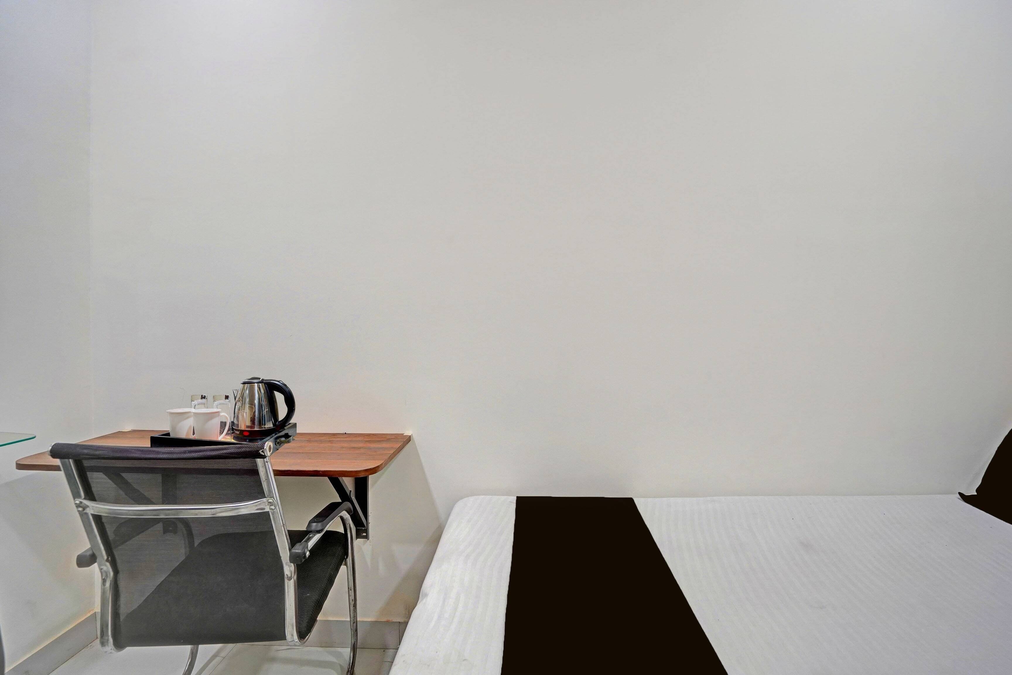Una habitación pequeña con una cama individual, un escritorio con una silla y una tetera sobre el escritorio.
