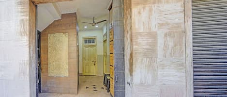 A hallway with a wooden door, a ceiling fan, and a tiled floor.