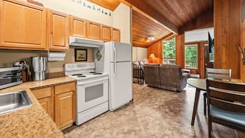 Une cuisine dotée de meubles en bois, d’une cuisinière, d’un réfrigérateur et d’un coin repas avec une table et des chaises.