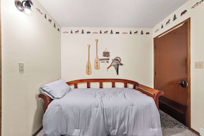 A bedroom with a bed, a wall-mounted fish-themed decoration, and a door. - Limber Pine Townhome and 2bdr Stay (Whitefish)