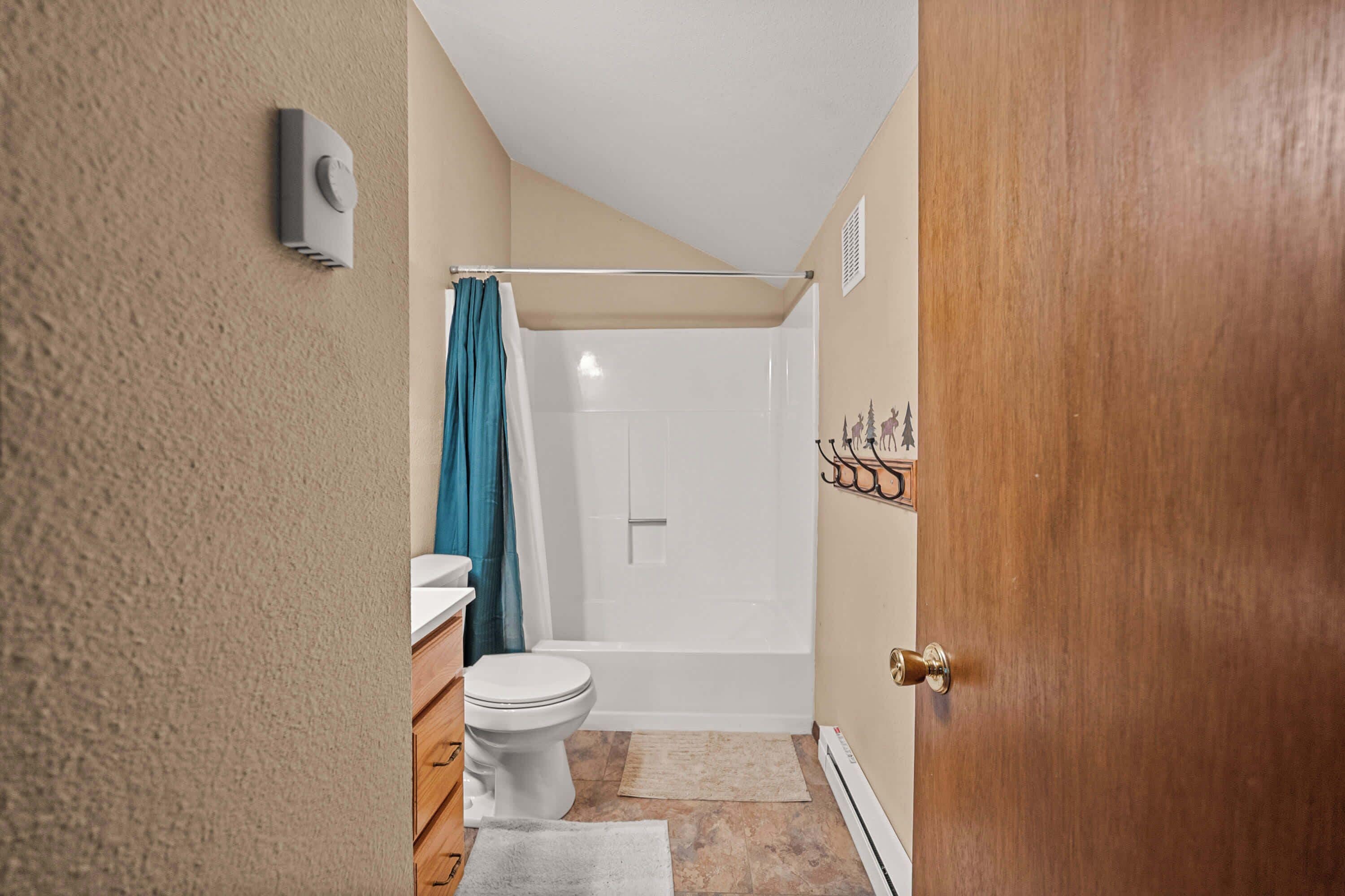 A bathroom with a toilet, sink, shower, and a towel on the floor.