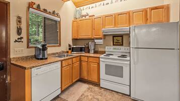 A kitchen with wooden cabinets, a white dishwasher, a stove, and a refrigerator.