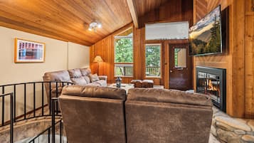 Un salon chaleureux avec une cheminée, des murs en bois et un manteau de cheminée en pierre.