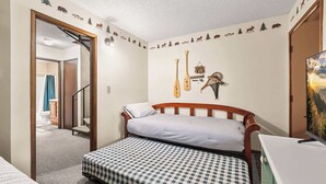 Een kamer met een bed, een bureau en een muur versierd met dieren en bomen.