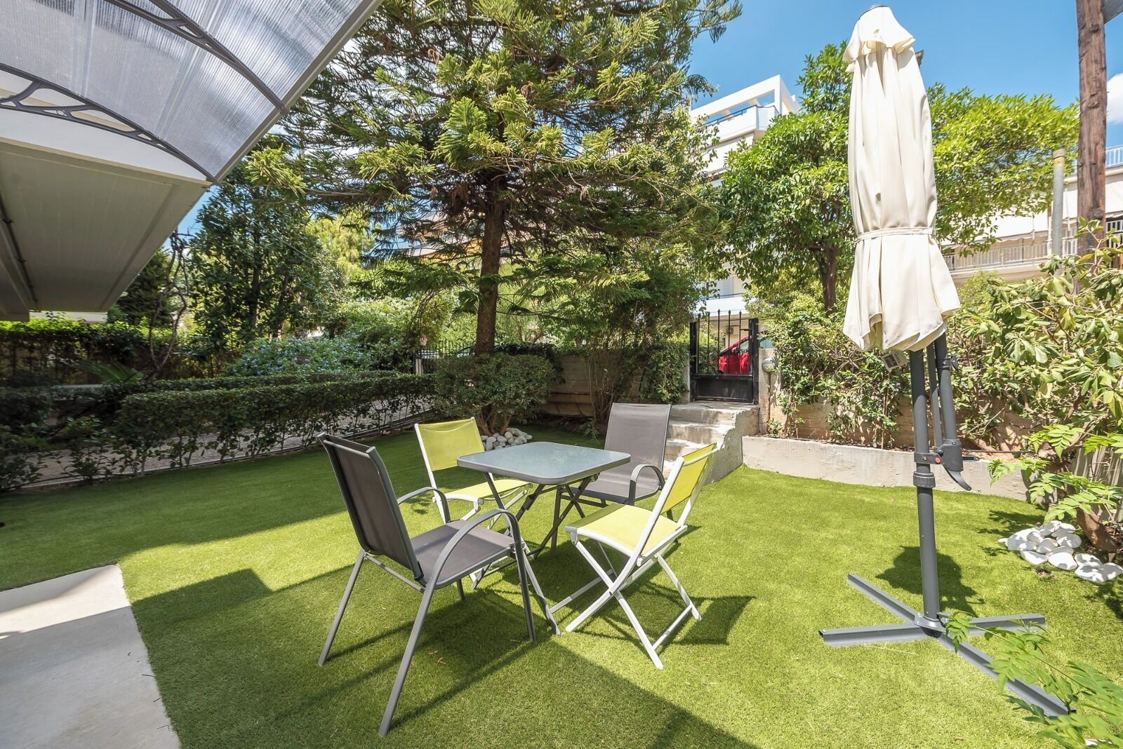 Une terrasse extérieure bien entretenue, avec une table et des chaises, entourée d’une végétation luxuriante et sous un ciel dégagé.