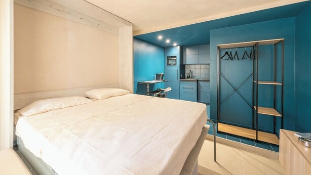 A bedroom with a bed, a desk, and a walk-in closet with hanging space. - Brand New Modern Studio in Faliro - 
Private garden (Paleo Faliro)