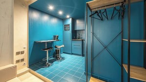 A modern bathroom with a blue wall, a shower area, and a sink. - Brand New Modern Studio in Faliro - 
Private garden (Paleo Faliro)