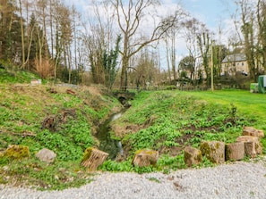 Un paisaje natural con un arroyo, árboles y una zona cubierta de hierba.
