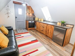 Una cocina compacta con armarios de madera, horno empotrado y lavavajillas de acero inoxidable.