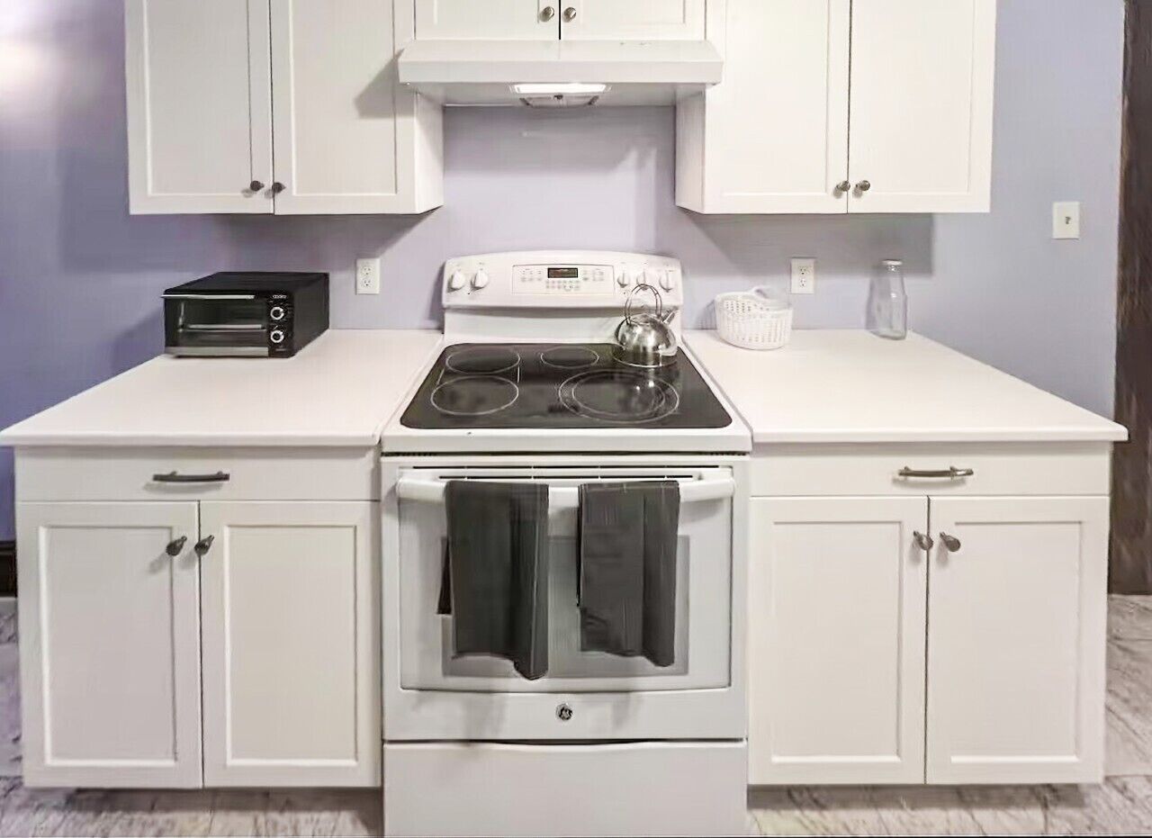 A kitchen with a white stove, oven, and cabinets.
