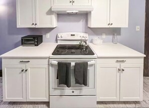 A kitchen with a white stove, oven, and cabinets.