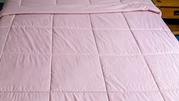 A bed with a pink quilt and two pillows.