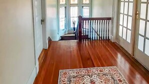 Un couloir doté d’un plancher en bois, d’un tapis à motifs et d’un escalier menant à l’étage supérieur.