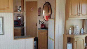 Cocina compacta con microondas, hervidor y refrigerador pequeño.