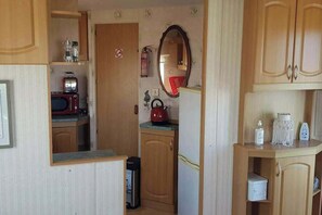A compact kitchen with a microwave, kettle, and a small refrigerator. - Donegal Coastal Mobile Homes With Private Garden (Letterkenny)
