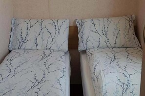 Two single beds with a tree branch pattern on the bedding, in a room with plain walls. - Donegal Coastal Mobile Homes With Private Garden (Letterkenny)