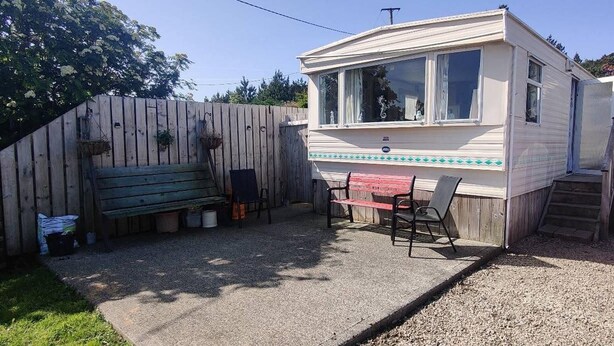 Una casa móvil con un patio, una pequeña mesa y sillas.