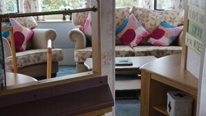 Una habitación con sofá, una mesita y un armario con una caja encima.