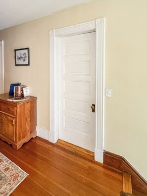 A room with a wooden dresser, a white door, and a framed picture on the wall. - YLD Rooms Rome - Shared Bath & Spaces (Springfield)