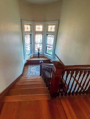 A wooden staircase with a handrail leading to a landing with three windows. - YLD Rooms Rome - Shared Bath & Spaces (Springfield)