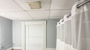A bathroom with a toilet, bidet, and a window with blinds.