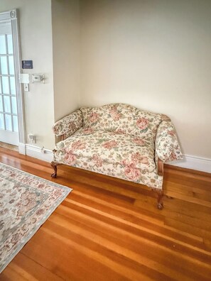 A room with a floral-patterned sofa, wooden flooring, and a rug. - YLD Rooms Rome - Shared Bath & Spaces (Springfield)